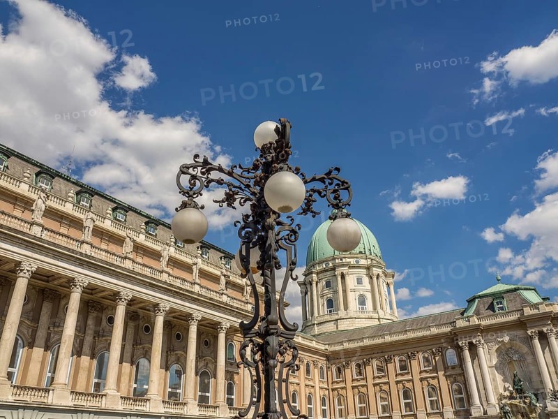 Historic castle with impressive dome and ornately forged lantern under a blue sky with white clouds, budapest, danube, hungary