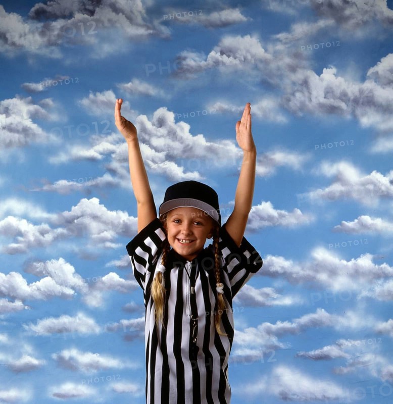 Smiling girl in referee outfit with hands raised against a vibrant sky, expressing joy and celebration