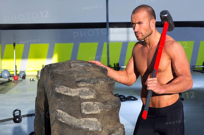 Crossfit sledge hammer man workout at gym relaxed after exercise