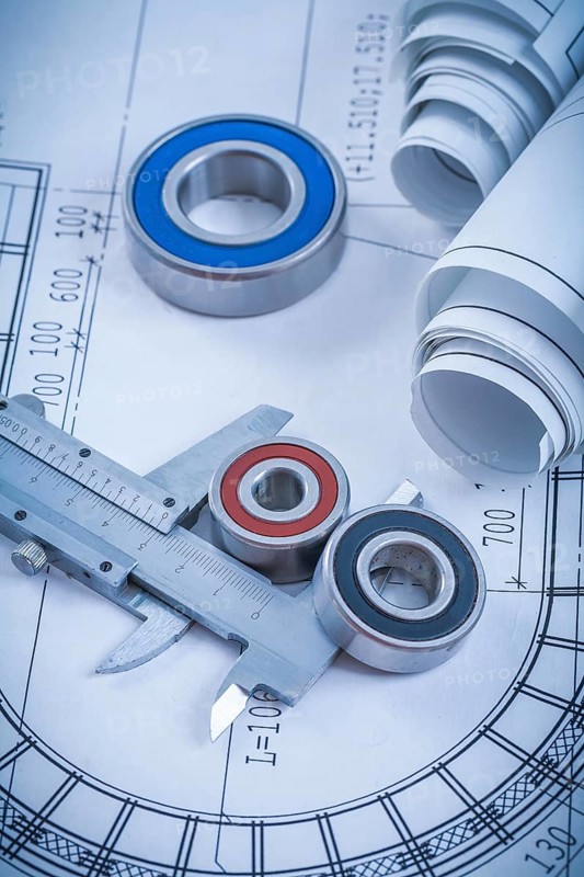 Rolls of construction drawings round rolling bearings and trammel caliper on blueprint industrial concept
