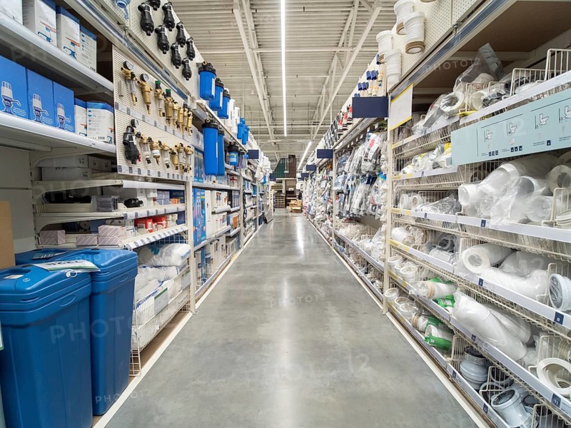 Store for home improvement and DIY. Warehouse aisle of building materials in industiral store. Bit dumpster, pipes. Shallow DOF