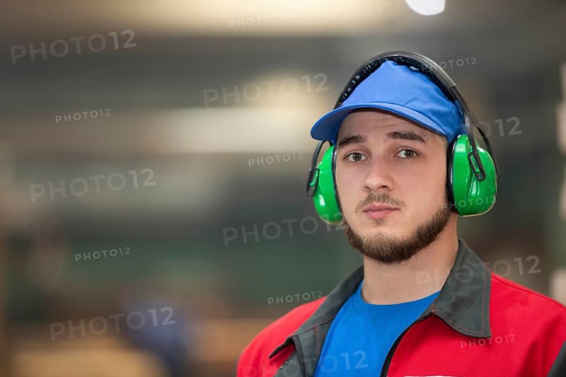 Belarus, Gomil. Wood processing plant. April 25, 2022.Close-up of a male worker wearing soundproof industrial headphones. Portrait of a worker standing in a factory in a workshop, Europe