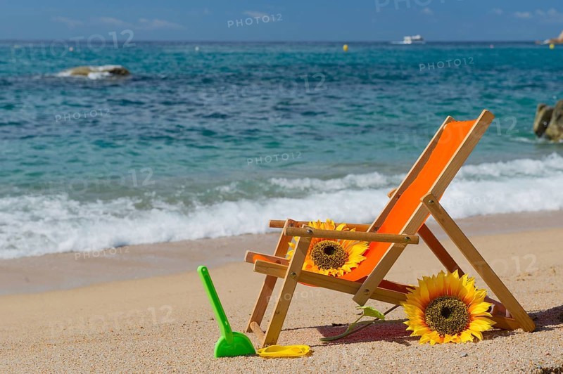 Empty beach chair with flowers and toys at the sea