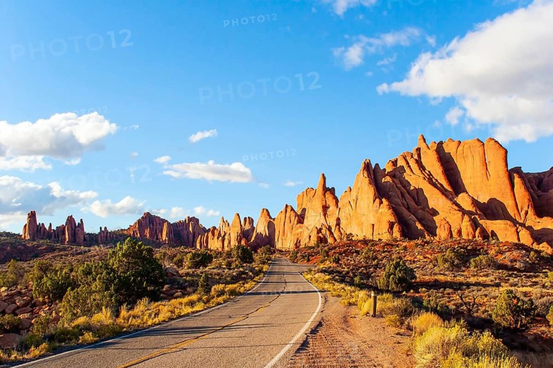 Asphalt road in the park. Arches Park in Utah, USA. Picturesque red-brown sandstone cliffs form a unique landscape. The unique beauty of Arches Park. Grandiose rock compositions natural origin