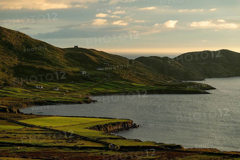 Coastal landscape on the Ring of Kerry near Waterville, with green fields and scattered houses in the evening light, Reenearagh, Iveragh Peninsula, County Kerry, Ireland, Europe