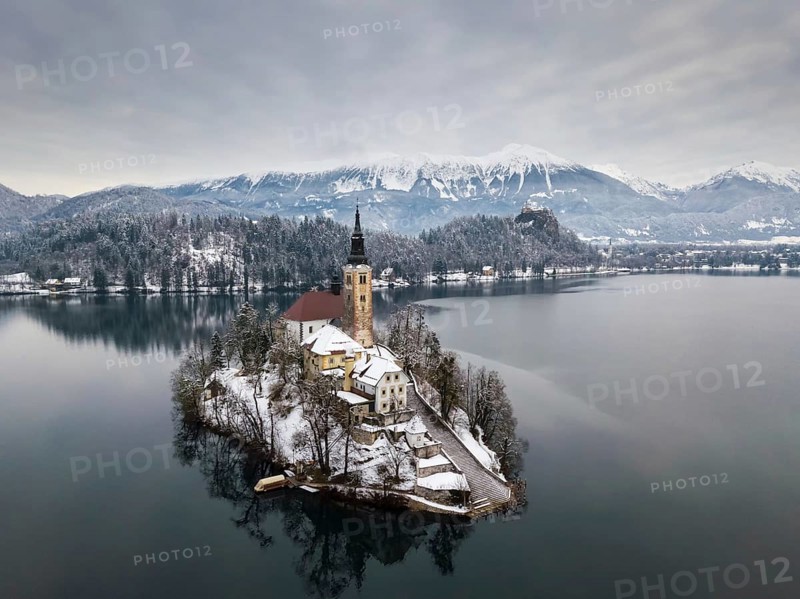 Aerial shot of lake Bled on a calm winter morning with snow