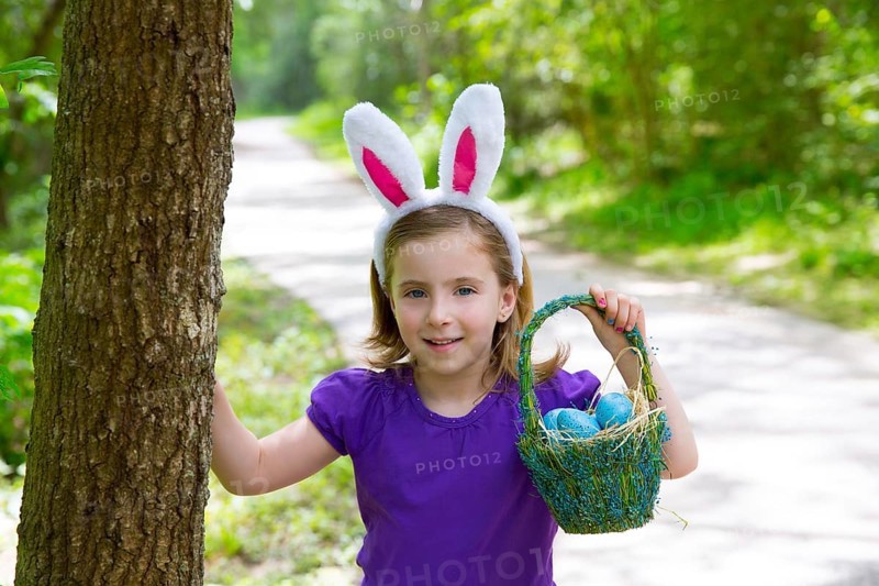 Easter girl with eggs basket and funny bunny ears on the forest