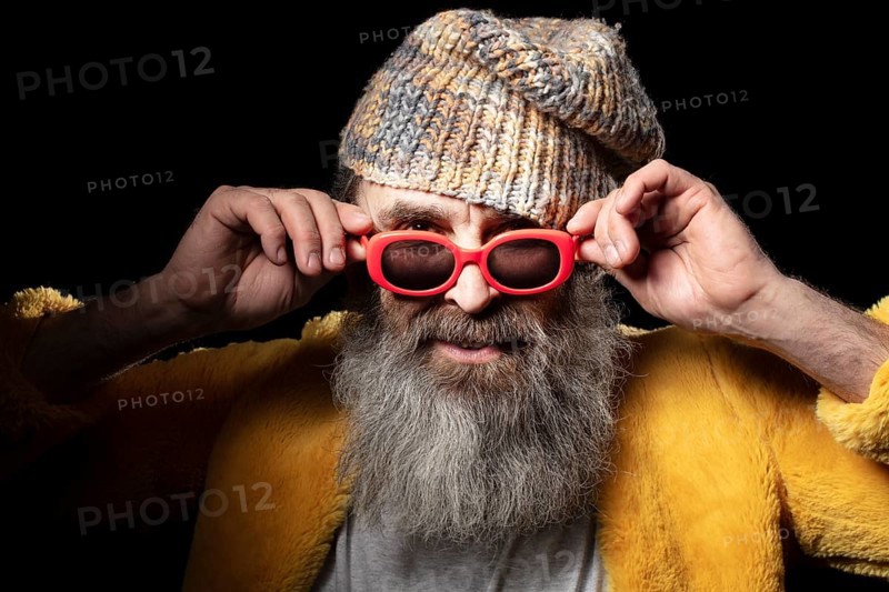 Fashionable older bearded man in light coloured clothes on a black background