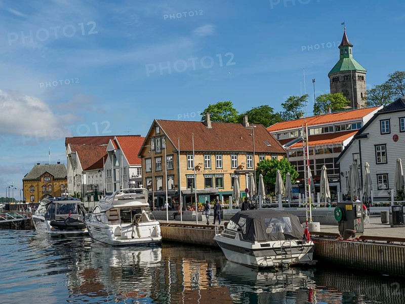 A harbour with several boats in front of colourful buildings under a blue sky with few clouds, Stavanger, Norway, Europe
