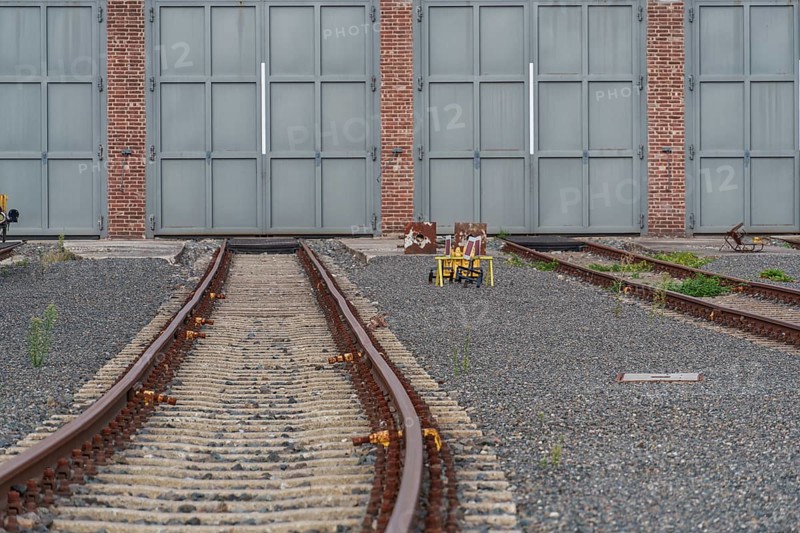 Empty rails lead to large grey doors on gravel, bochum, westphalia, germany