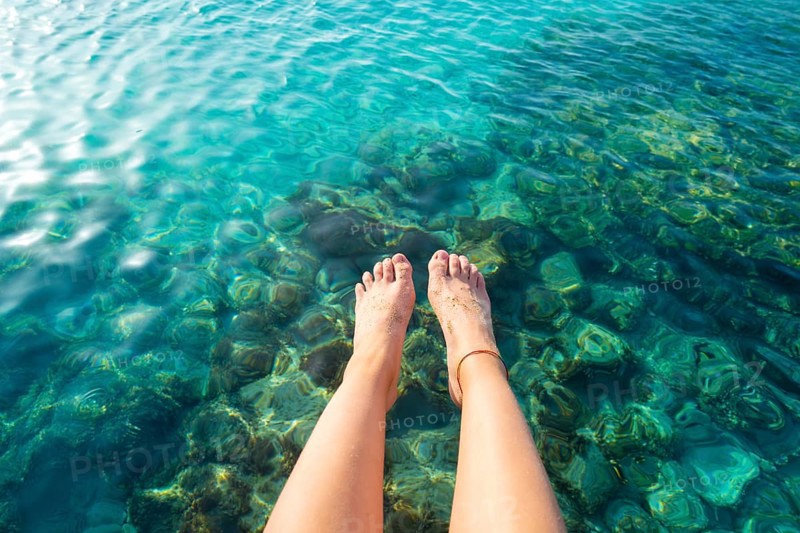 Ibiza girl legs at Portinatx beach pier clear water in Balearic Islands