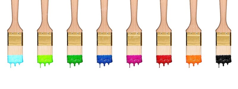 Colourful dropping set of paint brushes in a row isolated on white background