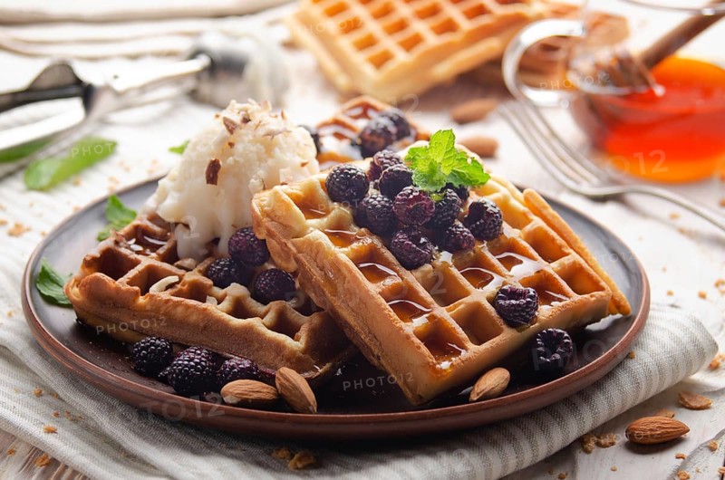 Homemade crispy Belgian waffles served with blackberries honey and icecream