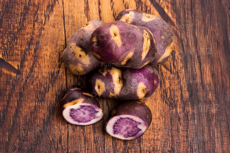 White - violet potato on wooden background. Organic plant