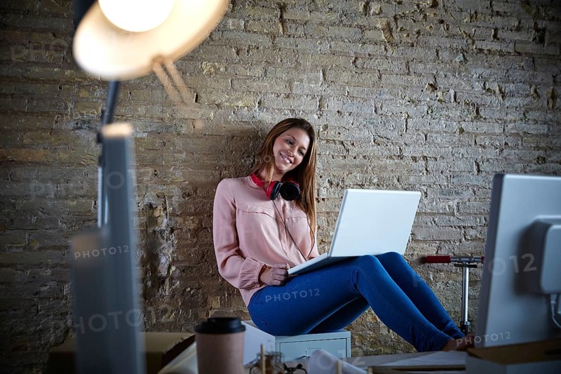 Businesswoman young casual sitting at office working with laptop computer feet on table relaxed