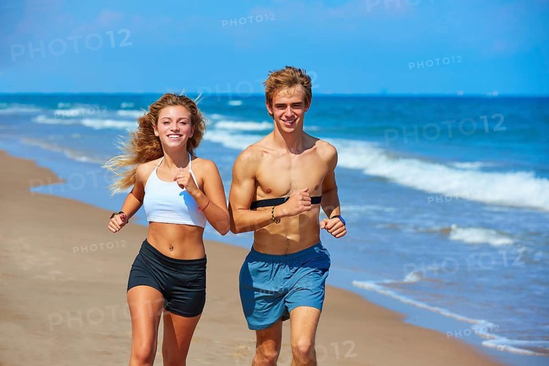 Blond young couple running on the beach in summer vacation