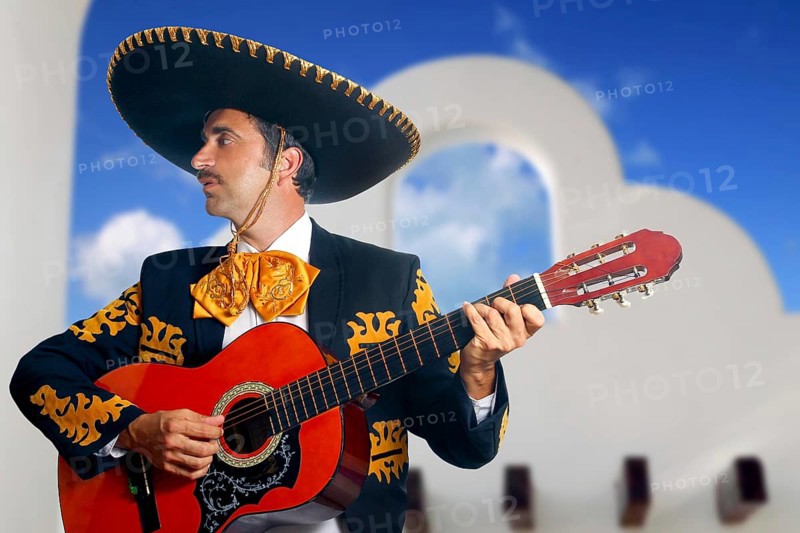 Charro Mariachi singer playing guitar in Mexico with white house background
