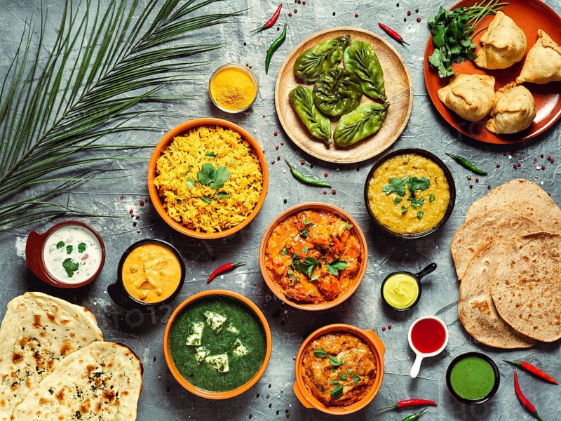 Indian cuisine dishes: tikka masala, dal, paneer, samosa, chapati, chutney, spices. Indian food on gray background. Assortment indian meal top view or flat lay
