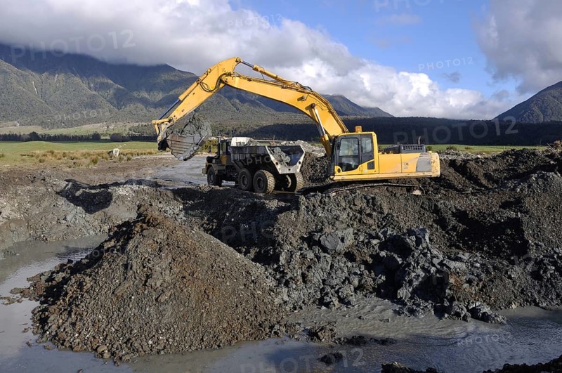30 ton digger collects blue clay for lining an effluent pond next to a rotary dairy in Westland, New Zealand, Oceania