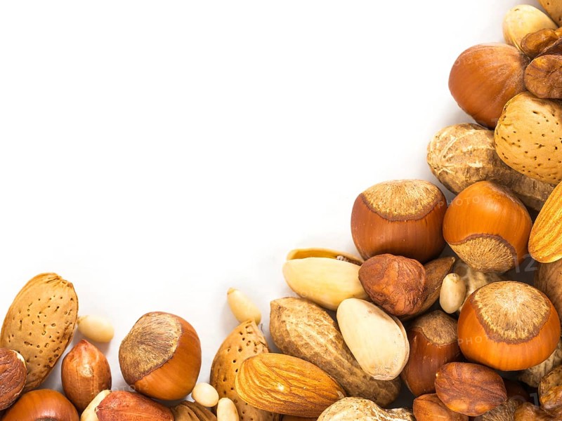 Background of closeup mixed nuts - hazelnuts, almonds, walnuts, pistachios, peanuts, pine nuts peeled and not peeled - with copy space. Isolated one edge. Top view or flat lay