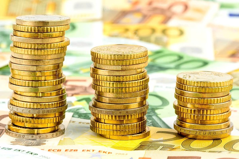 Stack of coins, falling curve, symbolic photo for falling interest rates and falling costs Austria