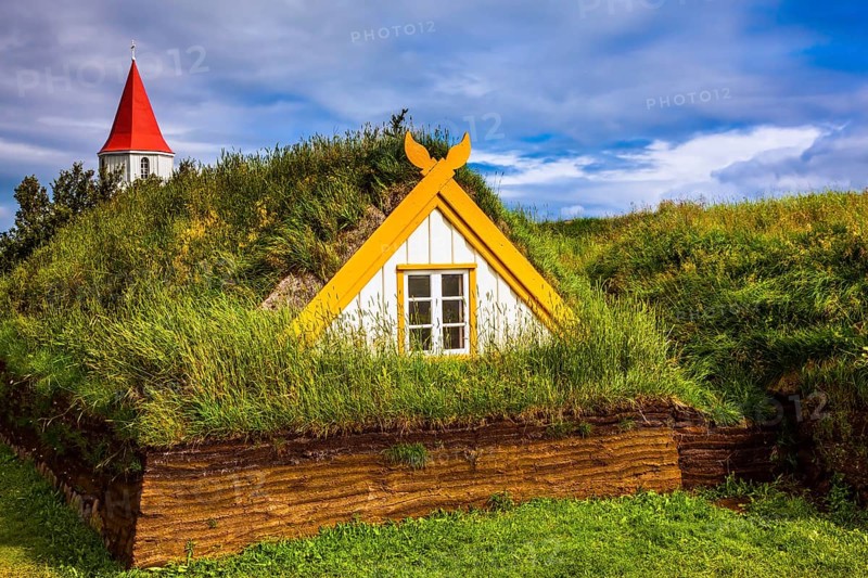 The village of houses covered with turf and grass. Church bell tower with red gabled roof. Ethnographic Museum-estate Glaumbaer, Iceland. The concept of the historical and cultural tourism