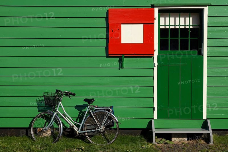 Bicycle parked in front of a green painted timbered house on the Dutch tourist attraction Zaanse Schans