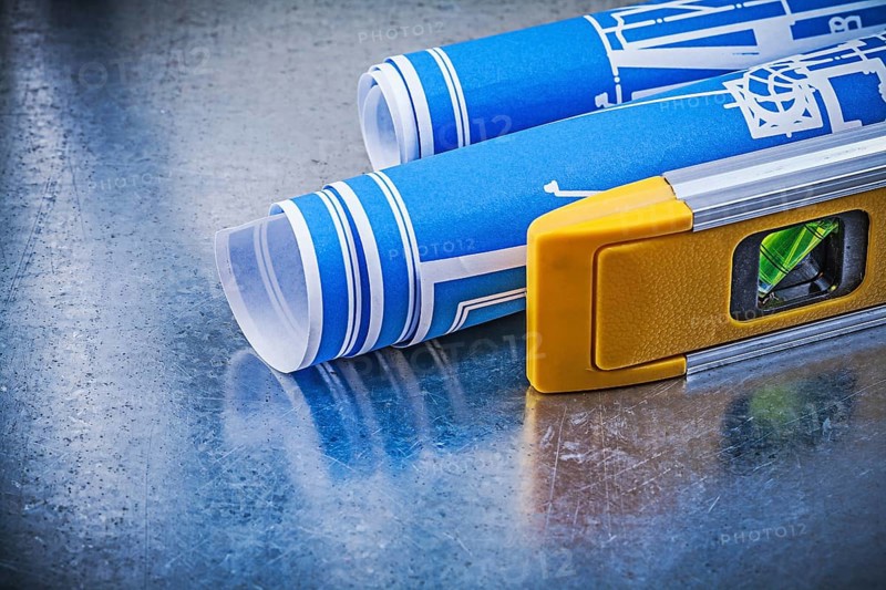Rolled up blueprints construction level on metallic background