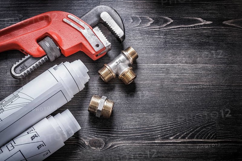Monkey wrench copper plumbing fittings rolled up construction plans