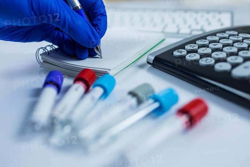 Close up photo of medicine bottles for samples next to computer tablet and computer keyboard in hospital or laboratory
