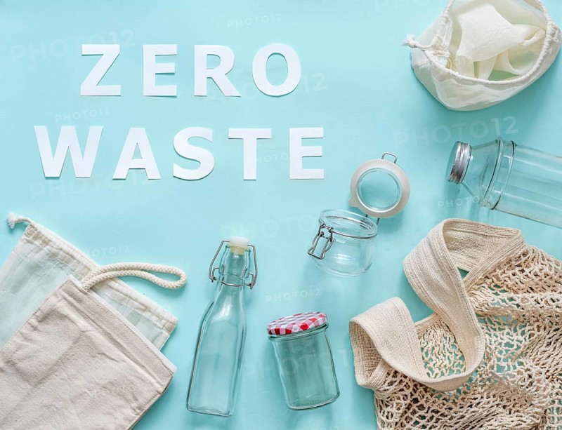Zero waste concept. Textile eco bags, glass jar and bottle on blue background with Zero Waste white paper text. Eco friendly and reuse concept. Top view or flat lay