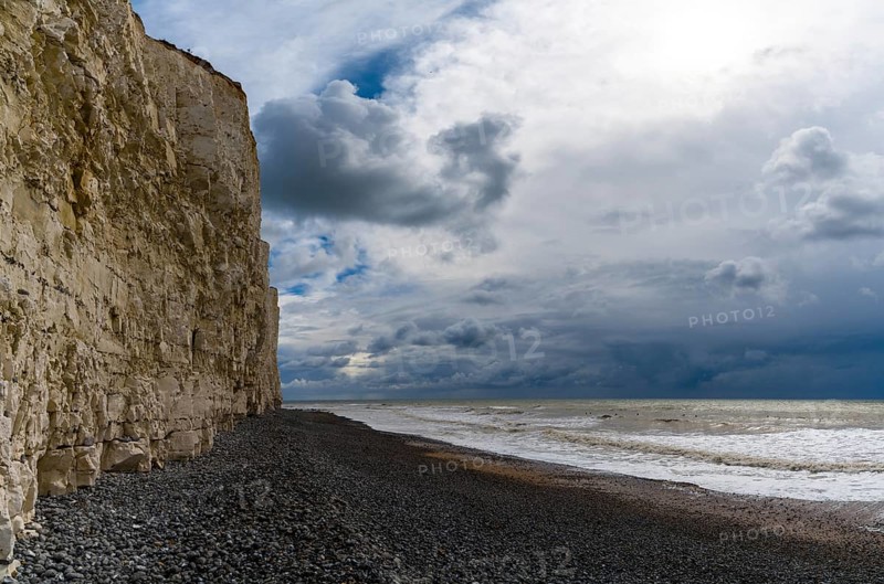 Landscape view of a black rock beach on the Jurassic Coast of England with tall chalkstone cliffs