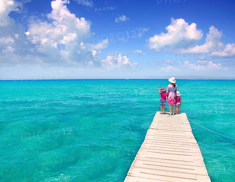 Daughters and mother in jetty on Formentera with turquoise sea