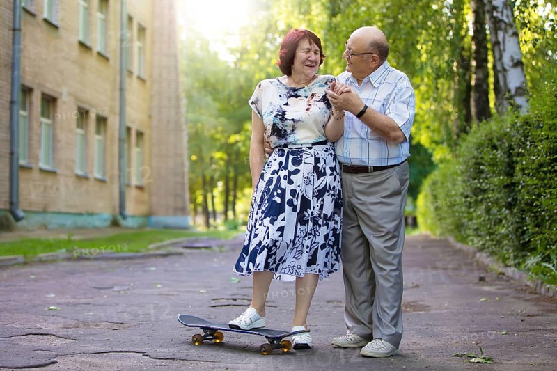 Happy elderly couple with a skateboard. Handsome man and woman seniors. Husband and woman in old age for a walk in the city
