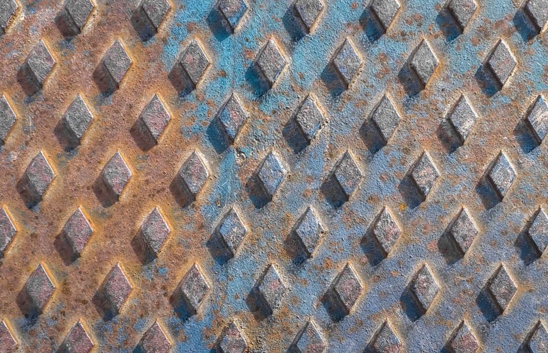Old rusty drain cover background with diamond pattern