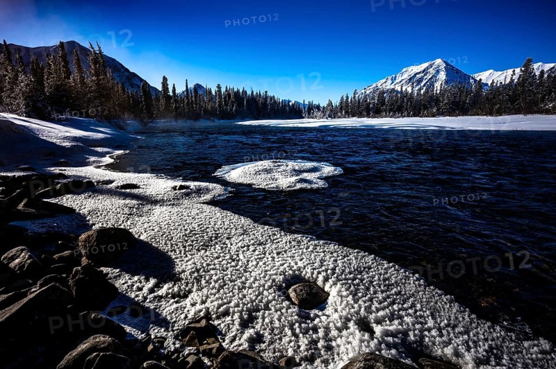 Snowy lake with mountains and forest under a clear blue sky, Yukon, Canada, North America