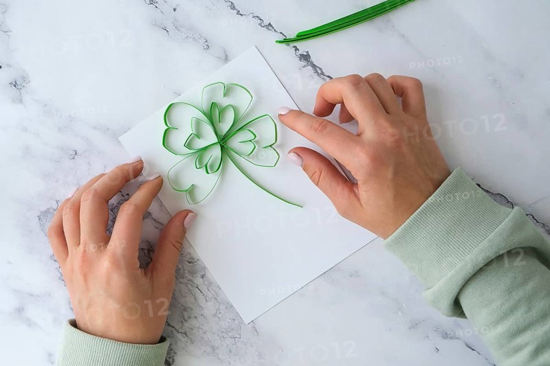 Diy St. Patricks Day greeting card made of Quilling and paper clovers on white background. Gift idea, decor Spring, happy Patrick Day. Step by step. Top view. Process kid children craft. Do it yourself
