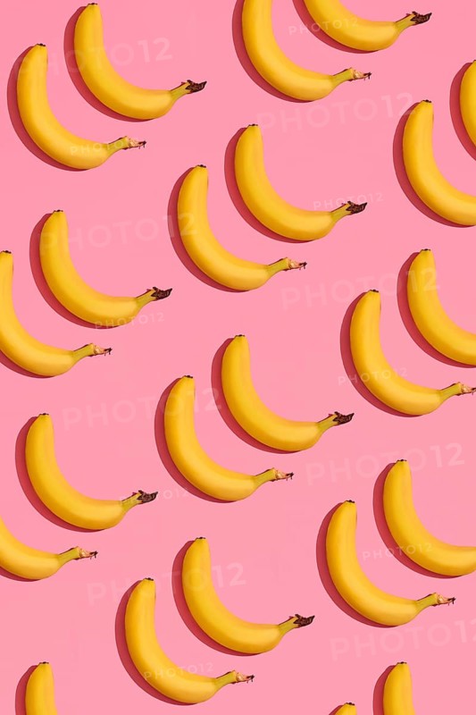 Food design. Pattern composition of a pair of bananas lying next to a pink background. Mock up, top view, flat lay style