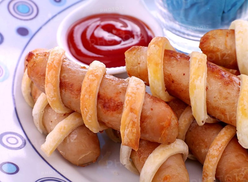 Fresh baked twisted pastry around chicken sausages with ketchup
