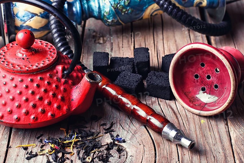 Details of Smoking hookah and red metal kettle spilled tea leaf