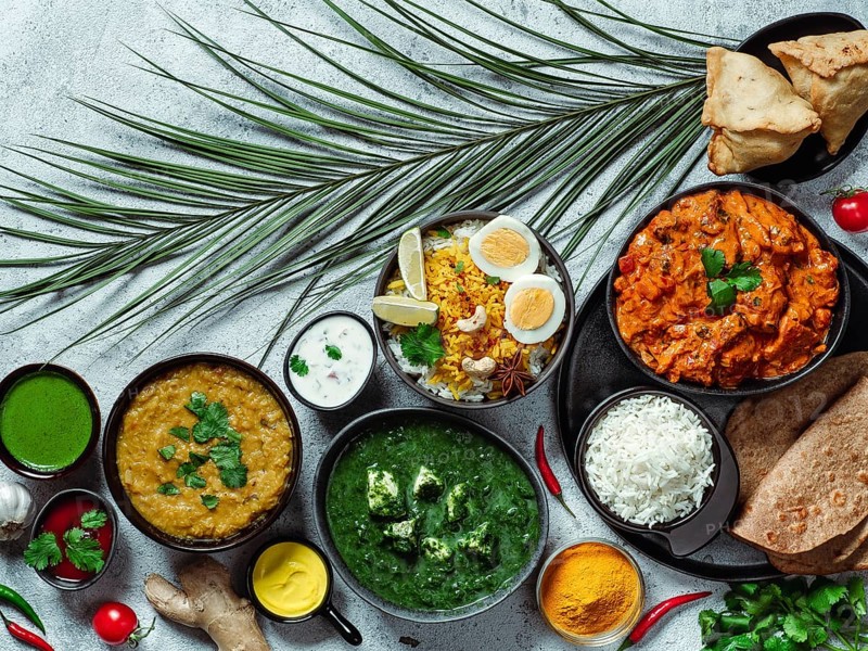 Indian cuisine dishes: tikka masala, dal, paneer, samosa, chapati, chutney, spices. Indian food on gray background. Assortment indian meal top view or flat lay. Copy space for text