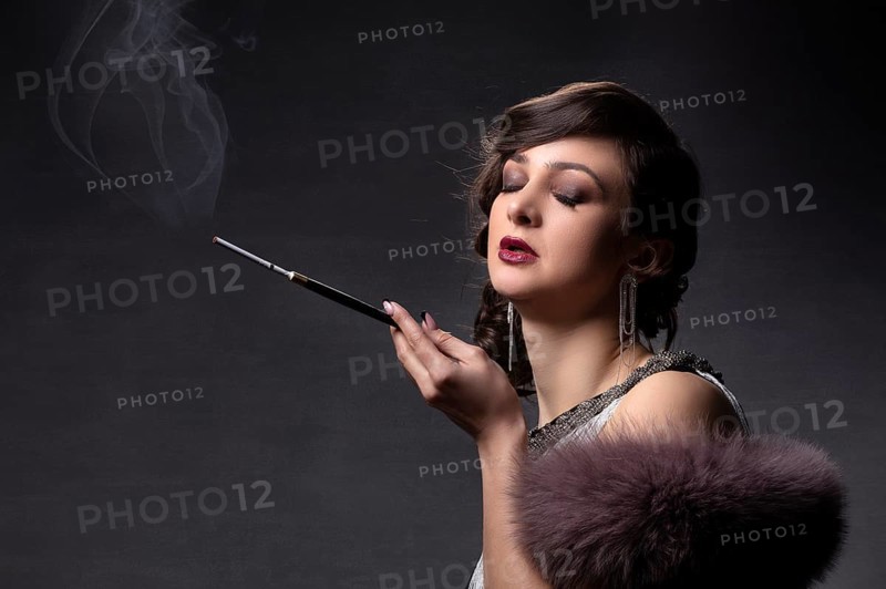 Retro portrait of a woman. A beautiful woman in the style of the 20s and 30s with a cigarette holder smokes