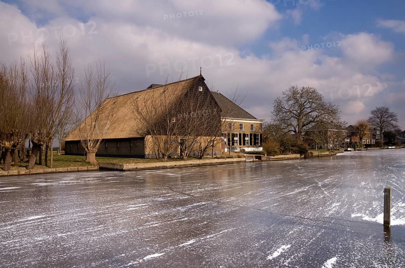 Frozen river the Graafstroom with on the other side a monumental farm in the South Holland village of Bleskensgraaf