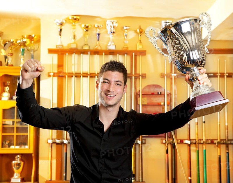 Happy proud winner man with big trophy silver cup in billiard club