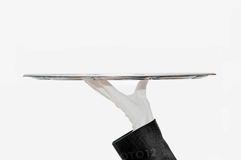 Waiter with white hemp shoes carries a silver tray
