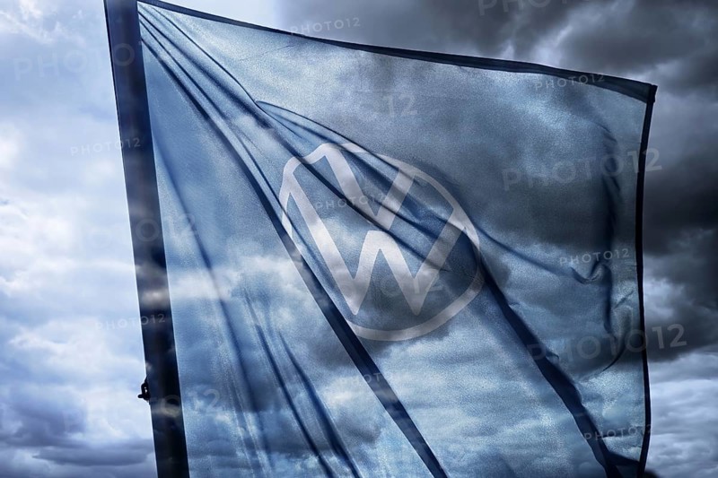 VW sign on the flag of a car dealer in front of a dark sky, symbolic photo VW crisis, photomontage