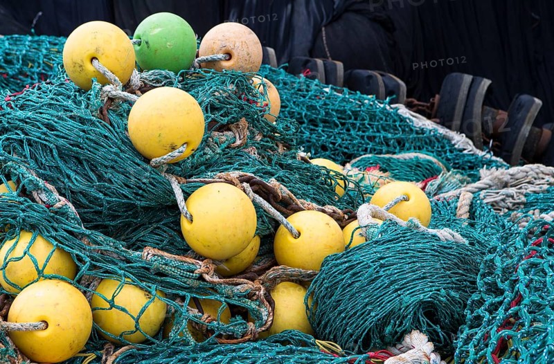 The photo shows a pile of fishing nets with floats