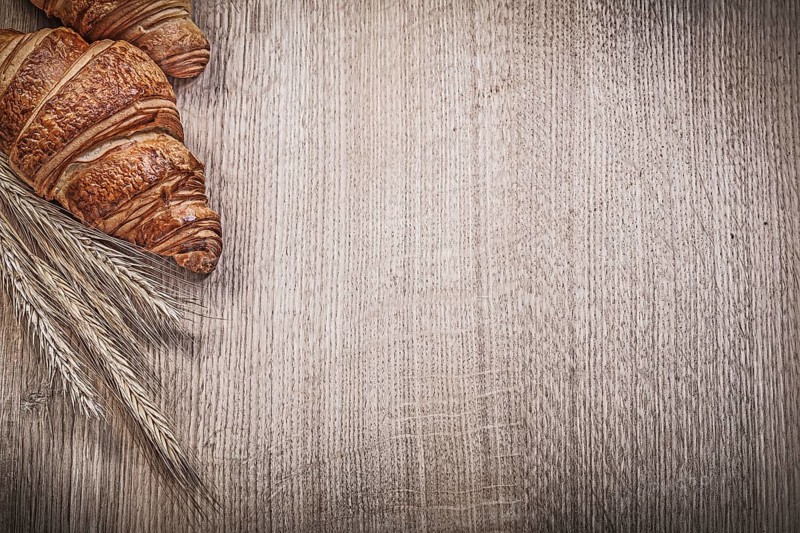 Ripe wheat rye ears fresh-baked croissants on wooden board