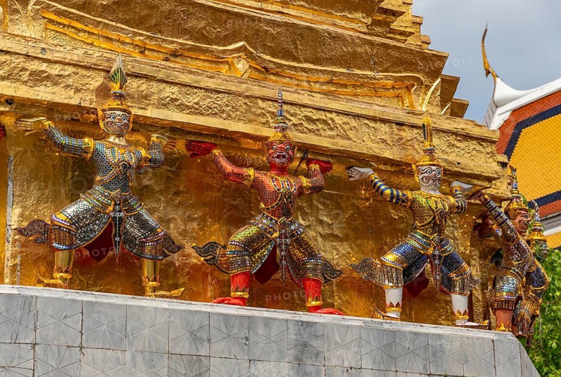 A picture of statues at the base of a golden chedi at the Grand Palace, in Bangkok