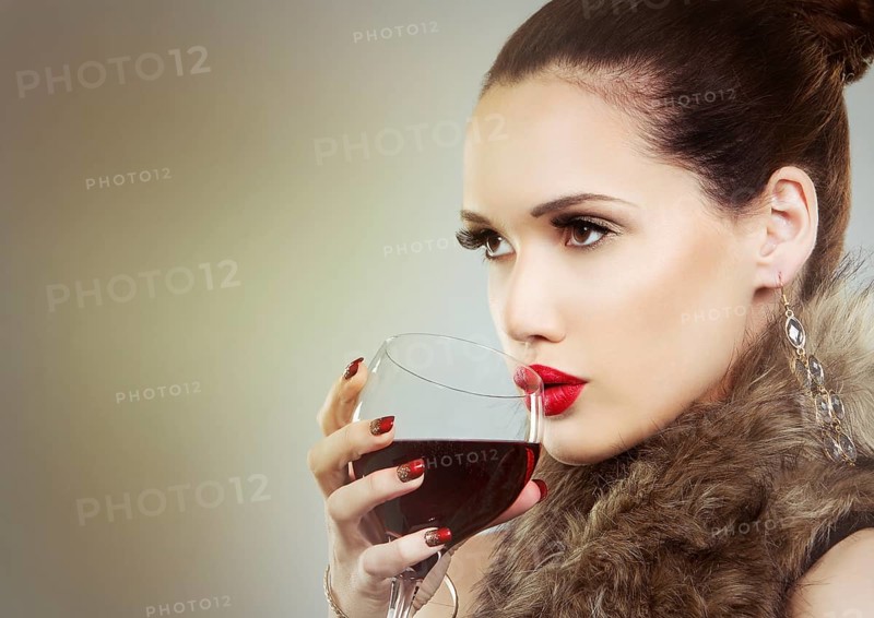 Beautiful woman with dark makeup and red lipstick posing on light grey background. Drinking glass of red wine, Toronto, Canada, North America